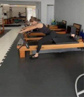 Aluna alongando no reformer durante aula de pilates na Ativa